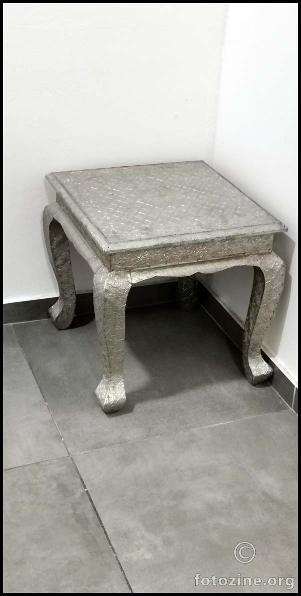 mali stolac srebrne boje u hodniku...