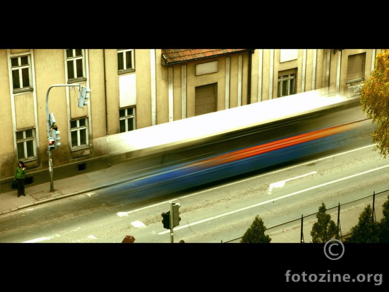 zena u zelenom ceka da prodje autobus